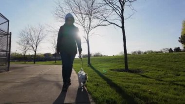 Woman walking the dog in the park. travel concept. Wide footage on sunset time. Slow motion. High quality 4k footage