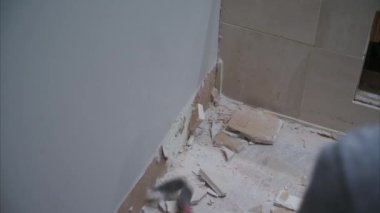 Odadaki bir duvarın yıkılması. Duvardan fayanslar sökülüyor. Evdeki dairenin sökülmesi ve yenilenmesi. Kapatın. Yüksek kalite 4k görüntü