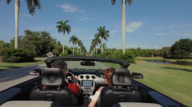 Mutlu çift gün batımında el sallayarak Cabriolet araba kullanıyor. Dikiz görüntüsü. Yüksek kalite 4k görüntü