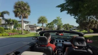 Cabriolet araba kullanan, el sallayan bir çift. Arka geniş açı. Yüksek kalite 4k görüntü