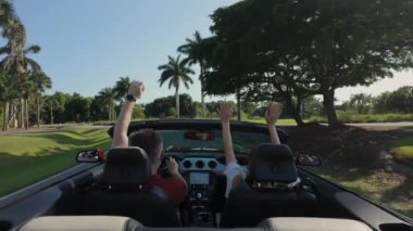 Cabriolet araba kullanan, el sallayan bir çift. Arka geniş görüntü. Yüksek kalite 4k görüntü