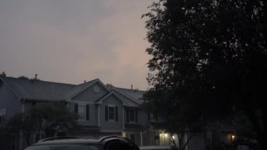 Akşamları banliyödeki caddede ağaçların arasından şimşek çakarken geniş bir görüntü. Yüksek kalite 4k görüntü