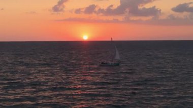 Sinema insansız hava aracı günbatımında denizde yüzen bir yelkenlinin geniş bir görüntüsü. Yüksek kalite 4k görüntü