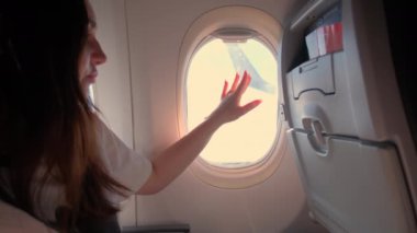 Genç bir kadın uçakta oturuyor ve kapı deliğinden bakıyor. Yüksek kalite 4k görüntü