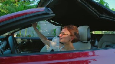 Cabriolet arabasında oturan kadın sürücü Üstü açılır Çatı 'yı açıyor. - Evet. Yüksek kalite 4k görüntü