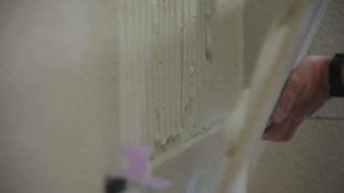 İşçi duvara büyük fayanslar koyar. Döşeme teknolojisi. Manzarayı kapat. Yüksek kalite 4k görüntü