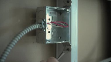 Profesyonel elektrikçi, yeni apartman duvarına yakın görüntüde renkli kabloları soket desteğine takıyor. Yüksek kalite 4k görüntü