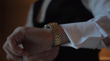 Damat bir sandalyeye oturur ve saati bileğine ayarlar. Yüksek kalite 4k görüntü