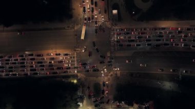 Hava aracı gece trafiğin yoğun olduğu kavşak boyunca tepeden aşağıya doğru uçuyor. Yüksek kalite 4k görüntü