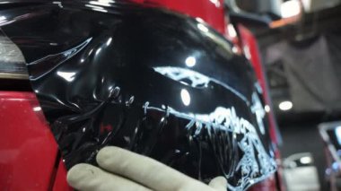 Ön taraftaki bir kamyona koyu PPF filmi uygulamak. Görüntüleri kapat. Yüksek kalite 4k görüntü