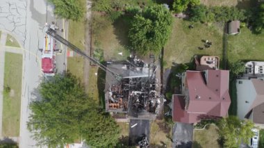 Yanmış ev ve itfaiyeciler ateşe su veriyor. Yukarıdan aşağıya insansız hava aracı görüntüleri. Yüksek kalite 4k görüntü