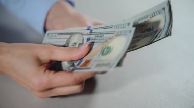 Kadın eli, elinde 100 dolarlık banknotlarla paraları sayıyor. Ağır çekim. Yüksek kalite 4k görüntü