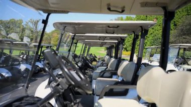 Golf arabalarının yakın görüntüsü belirlenen bölgede bir golf kulübünde. Oyuncuların sahada kullanması için düzgün düzenlenmiş elektrikli araçlar hazır.. 