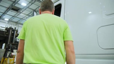 Bir tamirci ya da kamyon şoförü depoda ya da kamyon bakım merkezinde bir kamyona biniyor. Yüksek kalite 4k görüntü
