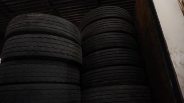 Büyük lastik yığınlarıyla dolu bir depo ya da depo. Lastikler üst üste yığılmış, derinlik ve şişkinlik hissi yaratıyor. Yüksek kalite 4k görüntü