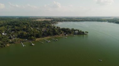 Her biri çeşitli boyutlarda teknelere ev sahipliği yapan suya uzanan birkaç rıhtımlı sakin göl manzarasının hava görüntüsü. Kıyı şeridi yemyeşil ağaçlarla kaplı. Yüksek kalite 4k görüntü