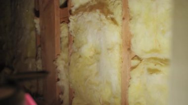 Bodrumdaki ahşap duvar çivileri ya da inşaat alanı arasına yerleştirilmiş sarı fiberglas yalıtım malzemesi. Kapatın. Yüksek kalite 4k görüntü