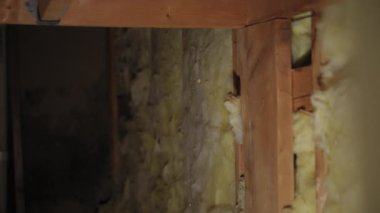 Bodrumdaki ahşap duvar çivileri ya da inşaat alanı arasına yerleştirilmiş sarı fiberglas yalıtım malzemesi. Manzarayı kapat. Yüksek kalite 4k görüntü