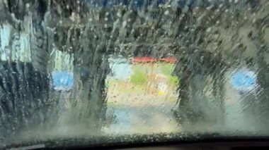 Otomatik oto yıkama sisteminden geçen bir arabanın içinden geniş çaplı görüntüler. Yüksek kalite 4k görüntü