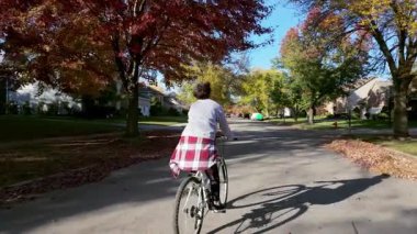 Banliyöde güneşli bir sonbahar gününün tadını çıkaran genç bir bisikletçinin arka görüntüsü. Yüksek kalite 4k görüntü