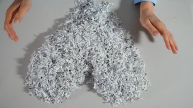 İşçi elleri parçalanmış ofis kağıtlarını kalp şeklinde düzenleyerek geri dönüşümü ve çevresel farkındalığı sembolize ediyor. Yukarıdan aşağıya doğru. Yüksek kalite 4k görüntü