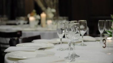 Restorandaki partide servis masası, bardaklar, tabaklar ve çatal bıçaklarla yakın çekim. Düğün, doğum günü, kutlama partisi. Kamera ağır çekimde hareket ediyor. Yüksek kalite 4k görüntü