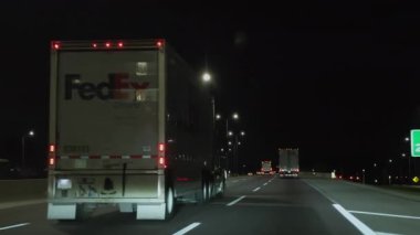 Gece vakti iyi aydınlatılmış otoyolda araba sürmek. FedEx 'le kovalamaca. İçerideki arabadan vurulmuş. Naperville lL 'de. ABD 20 Ağustos 2024. Yüksek kalite 4k görüntü