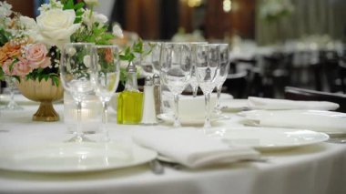 Kutlama partisinde servis masası, bardaklar, tabaklar ve çatal bıçaklarla yakın çekim sahnesi. Düğün, doğum günü, kutlama partisi. Kamera ağır çekimde hareket ediyor. Yüksek kalite 4k görüntü