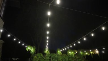 Festival dekoratif sicim ışıkları, sokak lambaları geceleri dışarıda parlıyor. Ilık ışıklandırma, klasik lamba çelengi, bayram ya da parti için dekorasyon. Yüksek kalite 4k görüntü