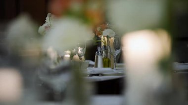 Restorandaki kutlama partisinde servis masasını gözlük, tabak, çatal bıçak ve mumlarla kapatın. Düğün, doğum günü, kutlama partisi. Ağır çekim. Yüksek kalite 4k görüntü
