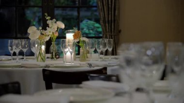 Restorandaki kutlama partisinde servis masası, bardaklar, tabaklar, çatal bıçaklar ve mumlar. Düğün, doğum günü, kutlama partisi. Kamera ağır çekimde hareket ediyor. 4k görüntü