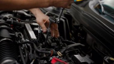 Tamircide arabanın kaputunun altında çalışan bir tamirci. Kapatın. Yüksek kalite 4k görüntü