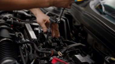 Tamircide arabanın kaputunun altında çalışan bir tamirci. Kapatın. Yüksek kalite 4k görüntü