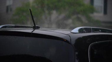 Şiddetli yağmur. Park yerindeki siyah arabanın üzerine yağmur damlaları düşer. Yağmur günü. Yüksek kalite 4k görüntü