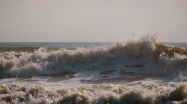 Fırtınalı ve rüzgarlı bir günde kumlu sahile devasa okyanus dalgaları çöker. Ağır çekim. Yüksek kalite 4k görüntü