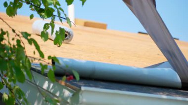 Roofer yapıştırıcı yüzeyi ile kaplı yeni bir çatı kuruyor. Kendi kendine yapışan çatı sistemi süreci. Yüksek kalite 4k görüntü