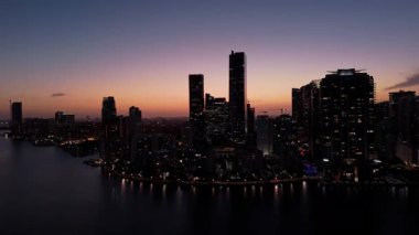 Alacakaranlıkta Miami sahilindeki modern gökdelenler renkli Sunset Light tarafından aydınlatılıyor. Yüksek kalite 4k görüntü