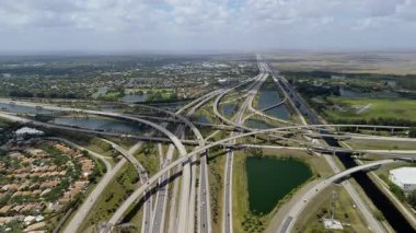 Miami 'de yükseltilmiş bir otoyol kavşağı, hareket halindeki araçlarla dolu, bulutlu bir gökyüzü altında ulaşım altyapısı sergileniyor. Yüksek kalite 4k görüntü