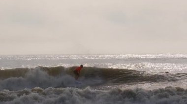 Sörfçü, Florida 'da güneşli bir günde fırtınalı okyanus dalgalarında ustaca sörf yapar. Jacksonville FL 'de. ABD 2 Nisan 2025. Yüksek kalite 4k görüntü