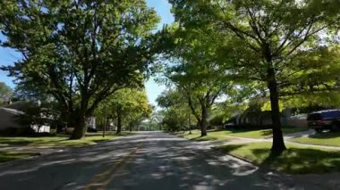 Hareket halindeki bir arabadan geniş çaplı bir görüntü, güneşli ve güneşli bir sabahta ABD 'deki bir parkın yakınındaki bir yerleşim yerini yakalıyor. Yüksek kalite 4k görüntü