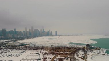 Chicago ufuk çizgisindeki karlı marina manzarası. Donmuş liman, arka planda yüksek binalar. Karda buzlu yeşil su birikintileriyle dolu boş rıhtımlar. Yüksek kalite 4k görüntü