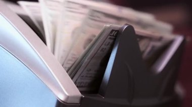 Para sayma makinesinin yan tarafı yakın çekim görüntüsü. Sayaç makinesi 100 dolarlık banknotları hesaplıyor. Ağır çekim. Yüksek kalite 4k görüntü