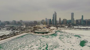 Chicago şehrindeki karlı bir marinanın gökyüzü manzarası. Donmuş göl, arka planda yüksek binalar. Karda buzlu yeşil su birikintileriyle dolu boş rıhtımlar. Yüksek kalite 4k görüntü