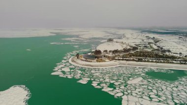 Chicago kentindeki karlı bir marinanın havadan görüntüsü. Donmuş göl, boş rıhtımlar ve buzun içinde buzlu yeşil su birikintileri. Yüksek kalite 4k görüntü