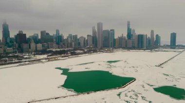 Chicago gökdelenli karlı marina manzarası. Donmuş göl, arka planda yüksek binalar. Karda buzlu yeşil su birikintileriyle dolu boş rıhtımlar. Yüksek kalite 4k görüntü