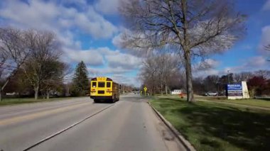 Çevresi sonbahar ağaçlarıyla çevrili banliyö caddesi boyunca hareket eden araçtan POV görüntüleri. Sıcak sonbahar renkleri ve parlak mavi gökyüzü mahallelerin güzel bir resmini oluşturur. Yüksek kalite 4k görüntü