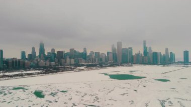 Chicago şehir silueti olan karlı bir marinanın havadan görüntüsü. Donmuş göl, arka planda yüksek binalar. Karda buzlu yeşil su birikintileriyle dolu boş rıhtımlar. Yüksek kalite 4k görüntü