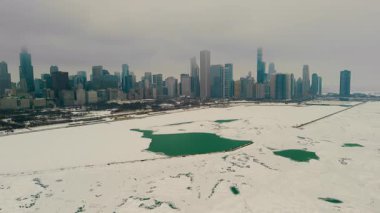 Chicago şehrinin gökyüzü karlı marina manzaralı. Donmuş göl, arka planda yüksek binalar. Karda buzlu yeşil su birikintileriyle dolu boş rıhtımlar. Yüksek kalite 4k görüntü