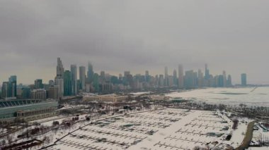 Chicago şehrindeki karlı marinanın gökyüzü manzarası. Donmuş liman, arka planda yüksek binalar. Karda buzlu yeşil su birikintileriyle dolu boş rıhtımlar. Yüksek kalite 4k görüntü