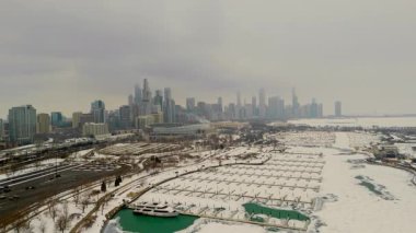 Chicago şehrindeki karlı bir marinanın gökyüzü manzarası. Donmuş liman, arka planda yüksek binalar. Karda buzlu yeşil su birikintileriyle dolu boş rıhtımlar. Yüksek kalite 4k görüntü